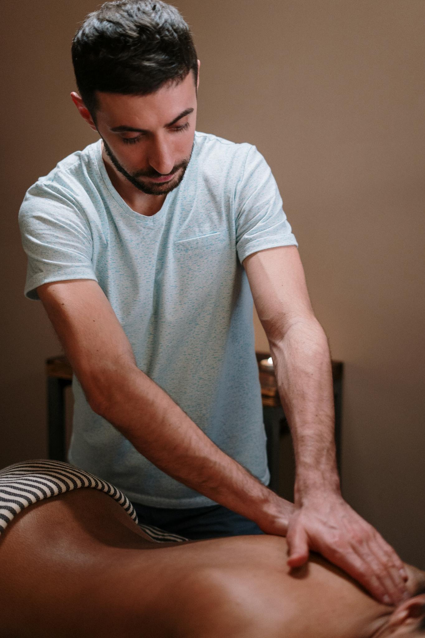 A male therapist providing a relaxing massage in a cozy spa setting.