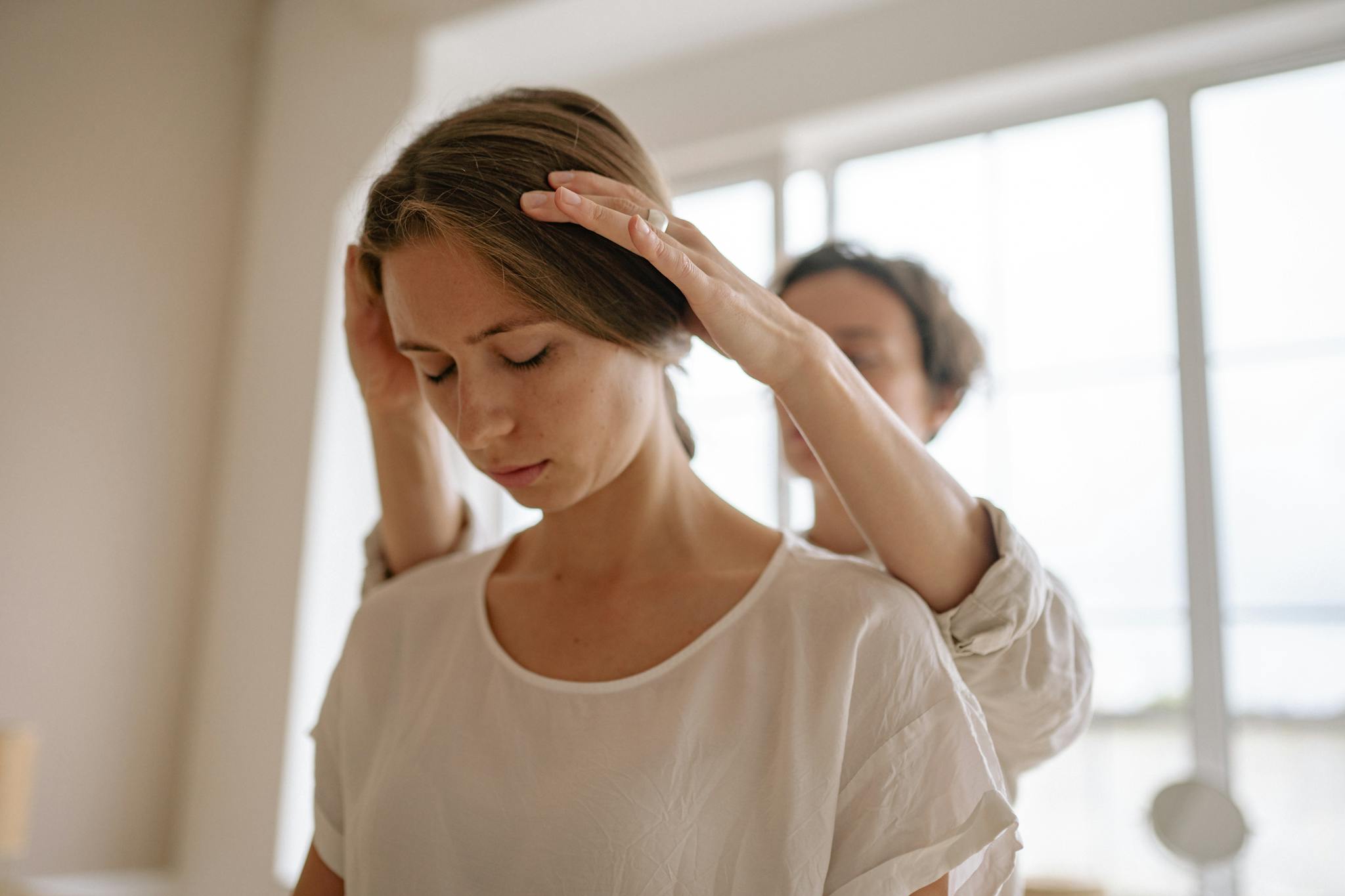 A serene moment of relaxation as a woman receives a gentle massage in a sunlit room.